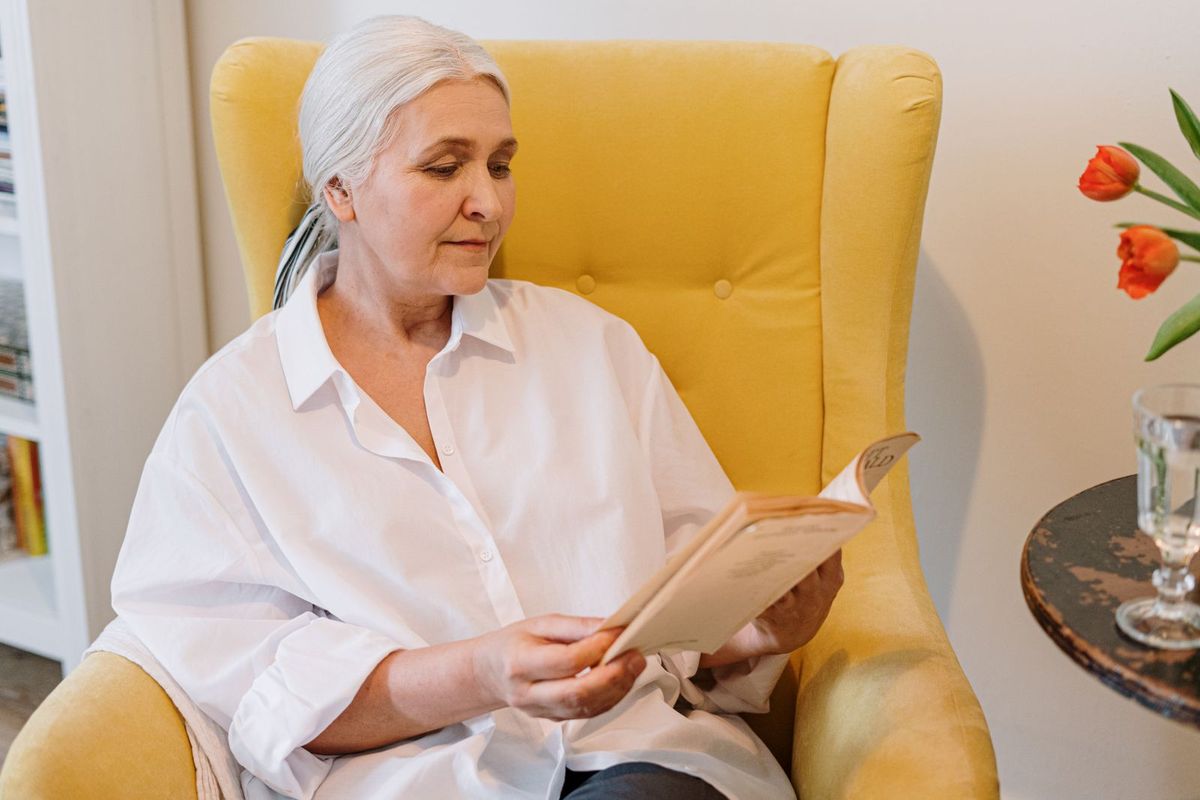 Frau über 60 liest im Sessel
