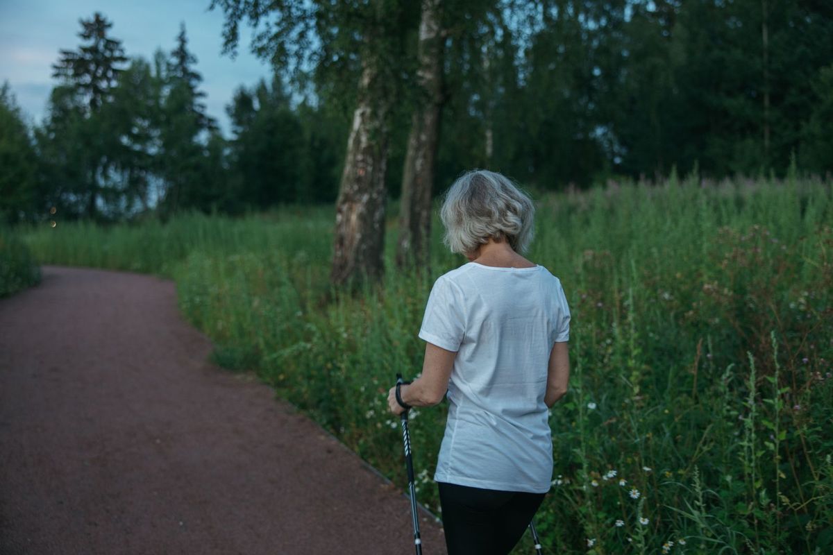 Frau beim Nordic Walking auf einem Waldweg