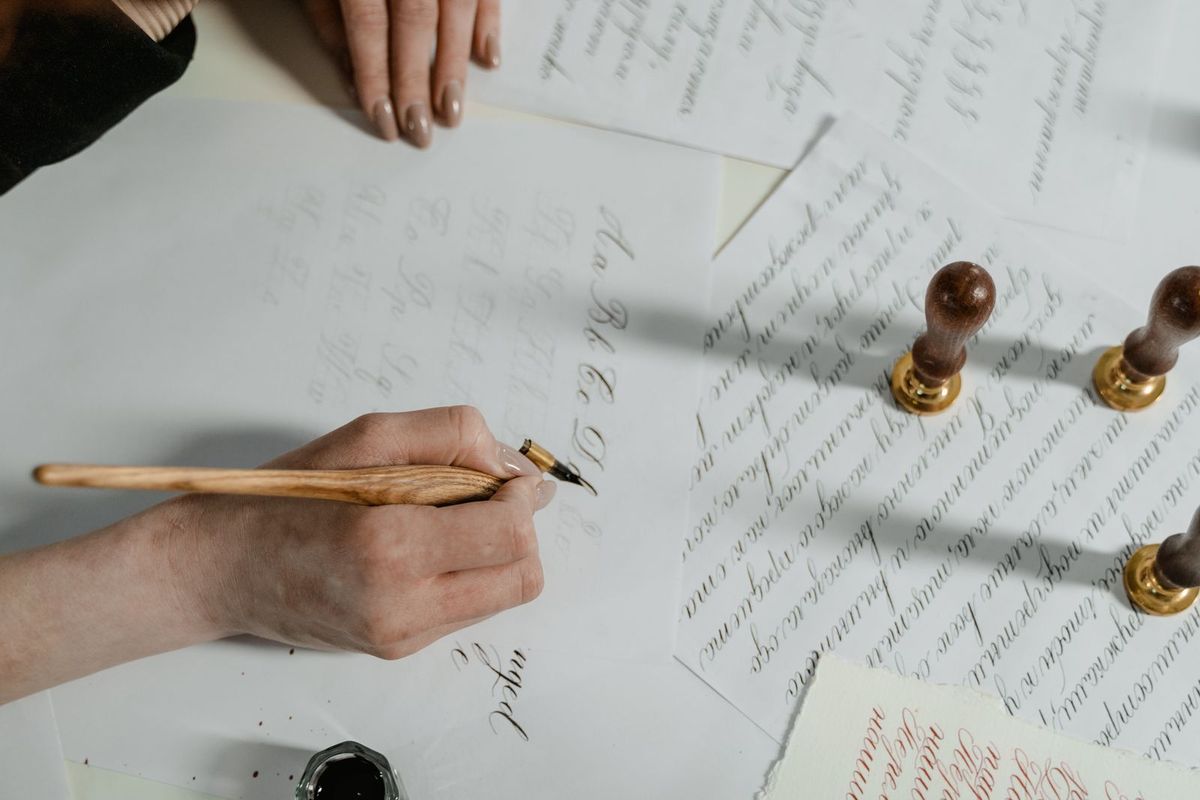 Hand schreibt mit Feder einen Brief