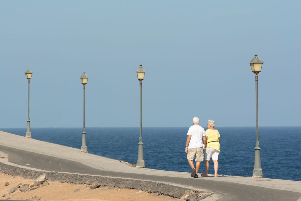 Paar über 60 spaziert auf einer Promenade am Wasser