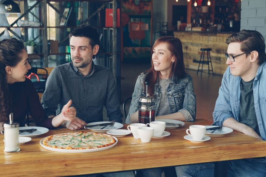 Gruppe im Gespräch an einem Tisch mit Pizza